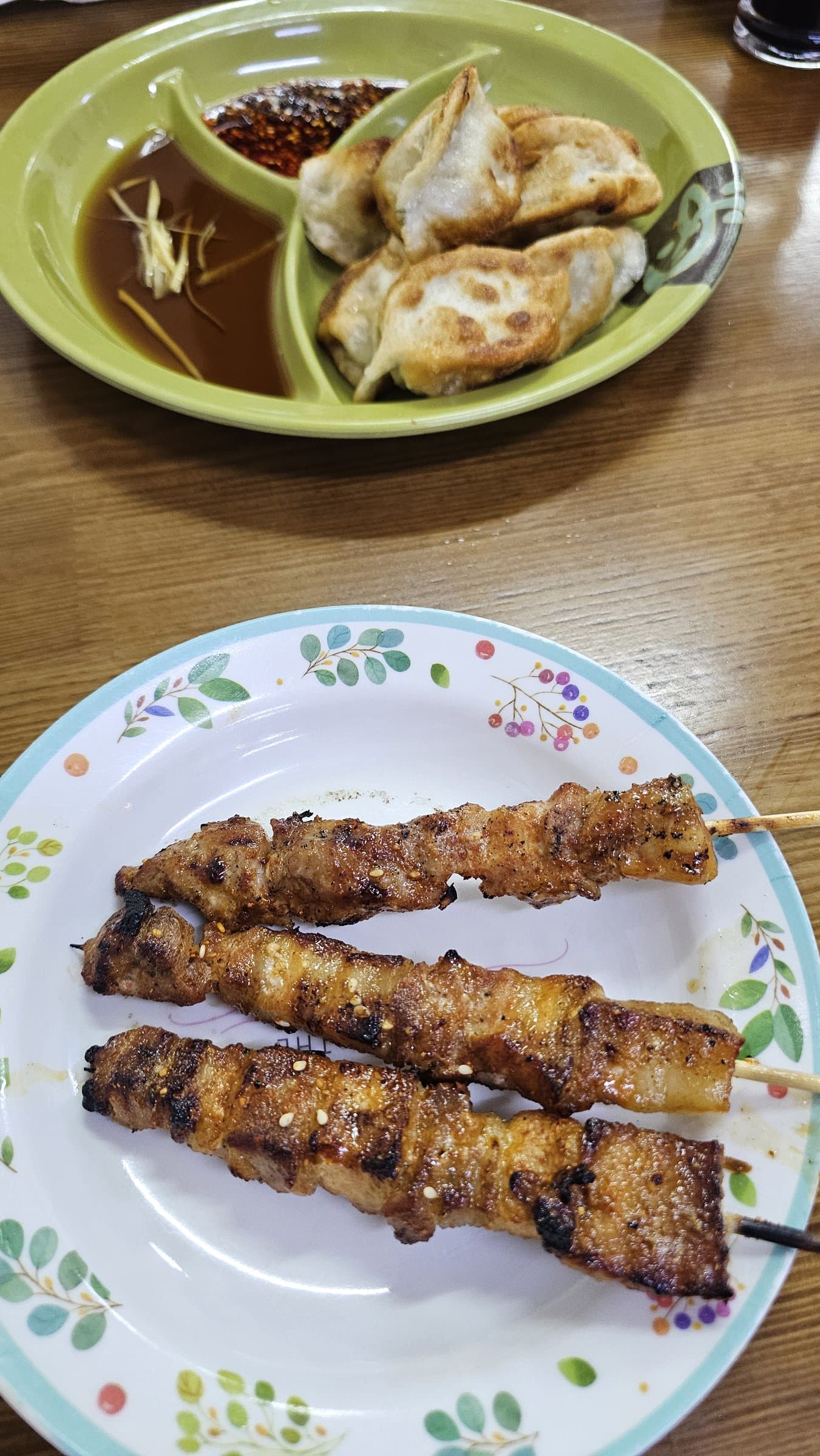 Grilled meat skewers and fried dumplings served on plates at a George Town hawker stall